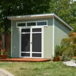 A modern outdoor wood shed featuring a door and a window, set against a natural backdrop