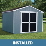 A small blue-gray storage shed with white trim and double doors, labeled INSTALLED, set in a grassy area.