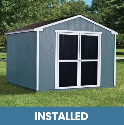 A small blue-gray storage shed with white trim and double doors, labeled INSTALLED, set in a grassy area.